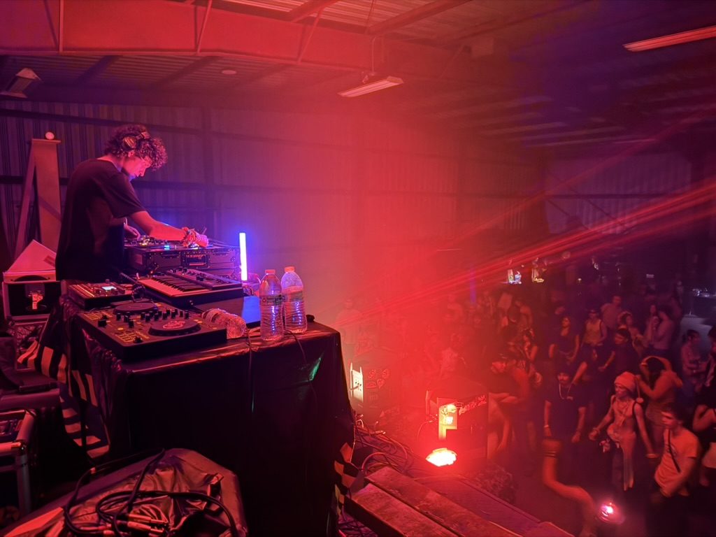 Live hardware performance above a warehouse crowd under red lights